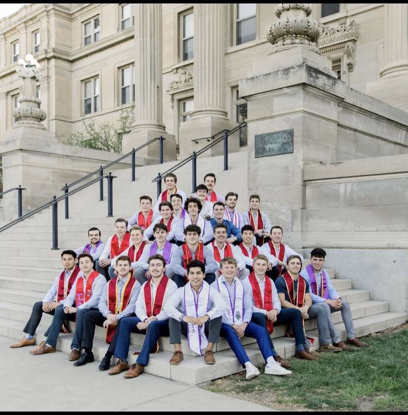 picture of male identifying students wearing fraternity stoles sitting on the steps of Curtiss Hall.