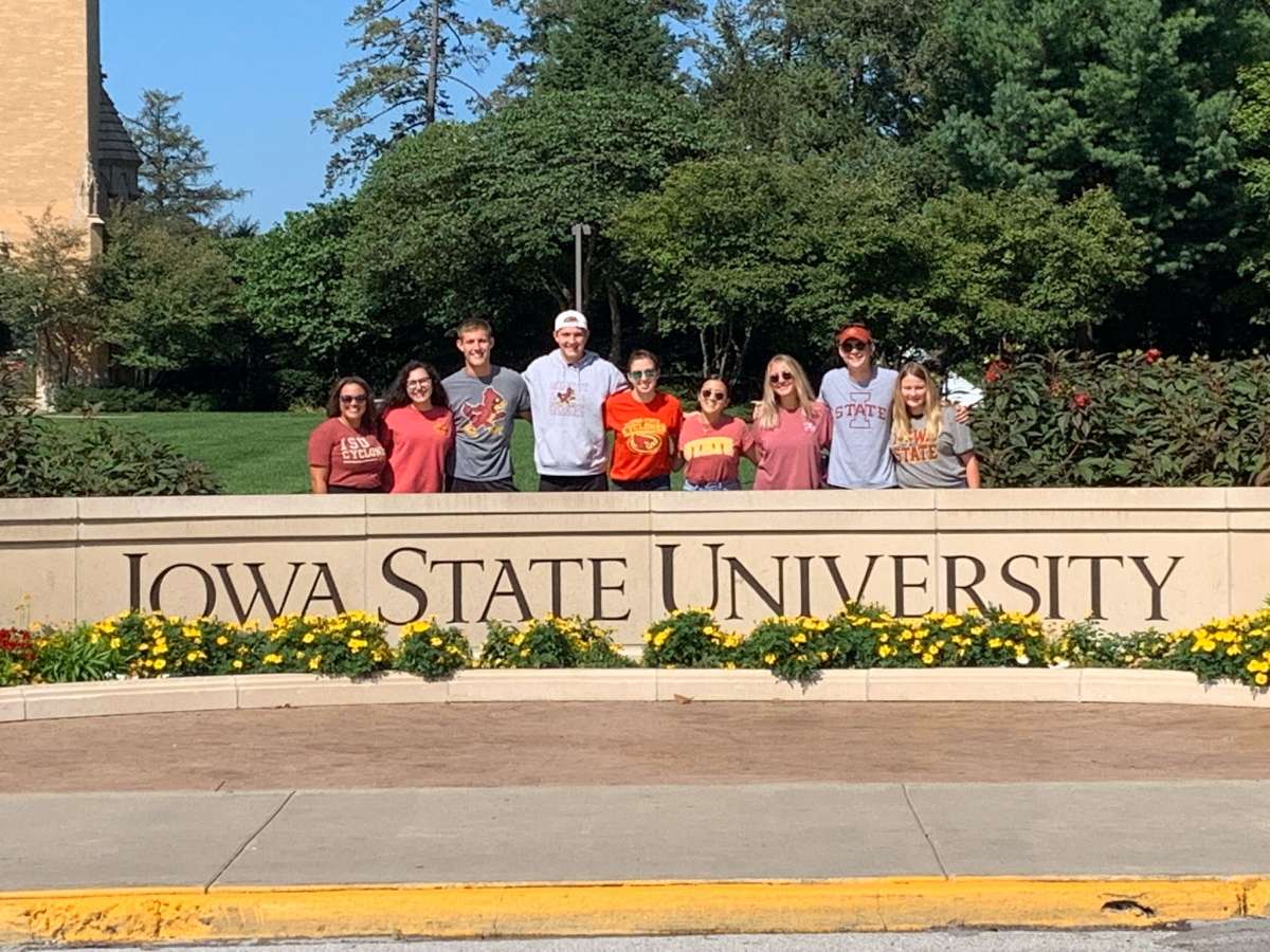 photo of students standing behind sign that says Iowa State University
